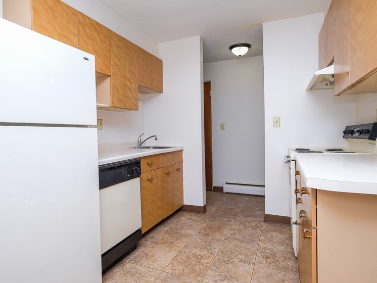 an empty kitchen with a refrigerator and a sink. Fargo, ND North Manor Apartments